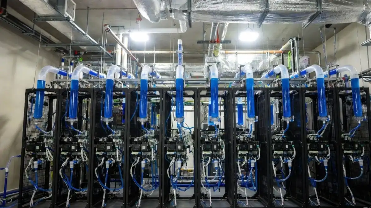 AI server racks fitted with clear coolant pipes carrying blue liquid for direct liquid cooling, a closed loop that reduces water use at the rack