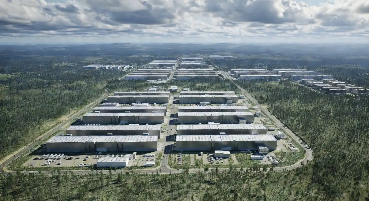 Aerial view of rows of large data-centre buildings cleared into a forest landscape