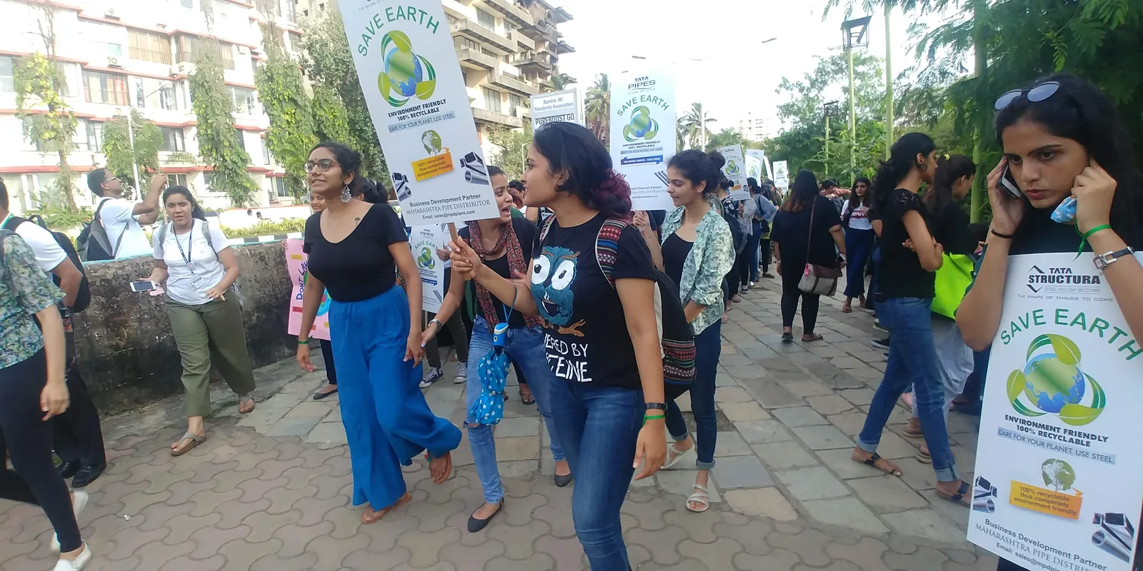 High school marketing internship field work. Volunteers walking with placards in an environmental awareness rally