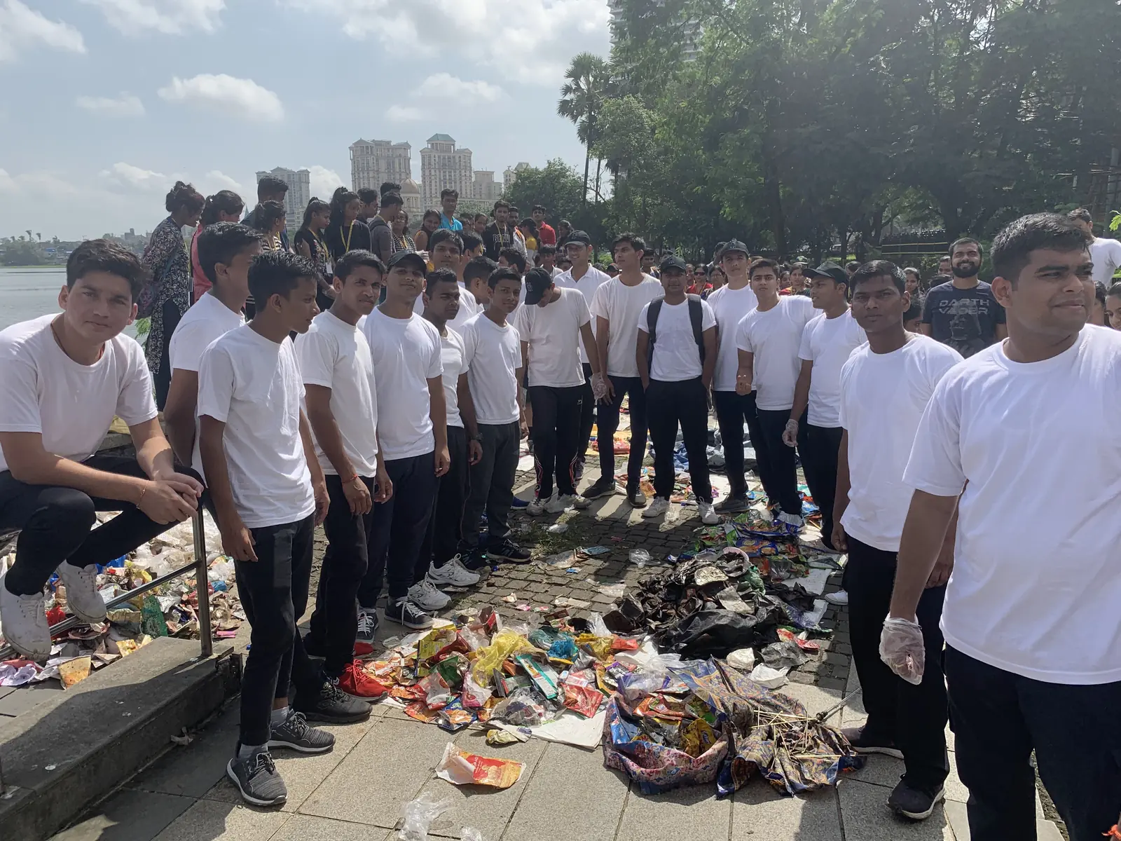 Line of corporate volunteers in white T-shirts behind a row of sorted waste from their cleanup