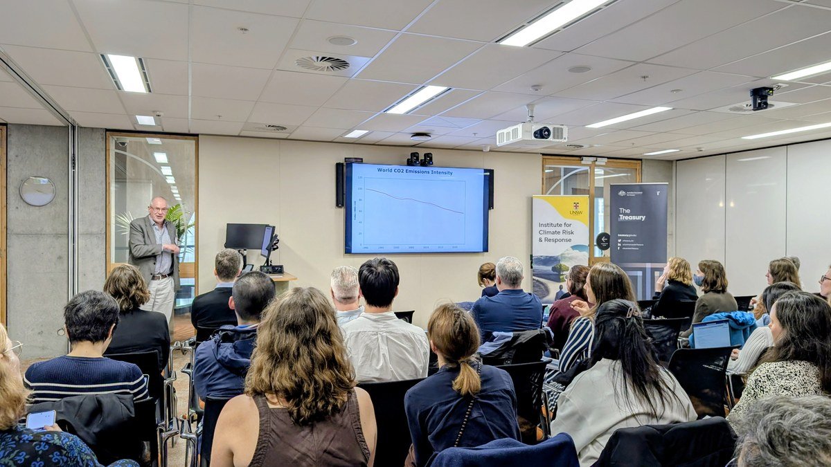 David Stern presenting to a full room at UNSW Sydney, with a slide titled World CO2 Emissions Intensity showing a falling trend line