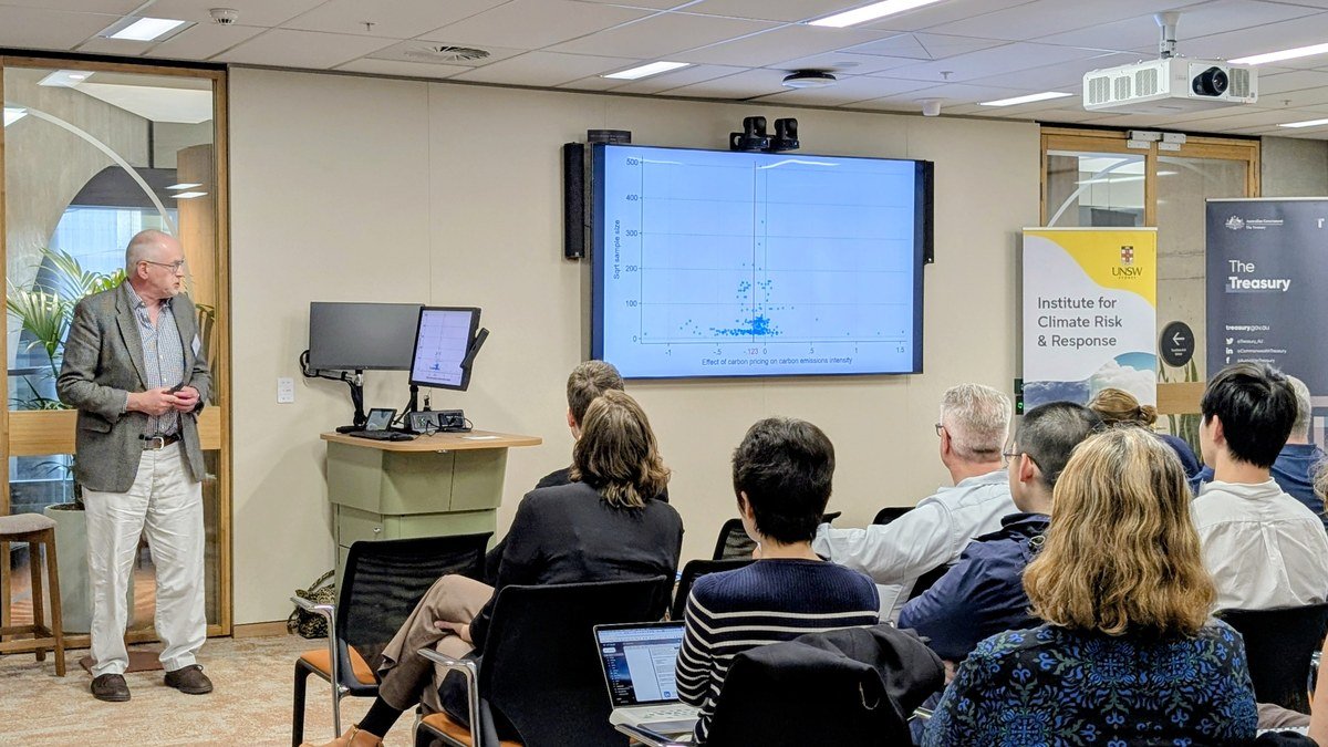 David Stern presenting a scatter plot on the effect of carbon pricing on carbon emissions intensity to an audience at UNSW Sydney, with UNSW Institute for Climate Risk and Response and Treasury banners