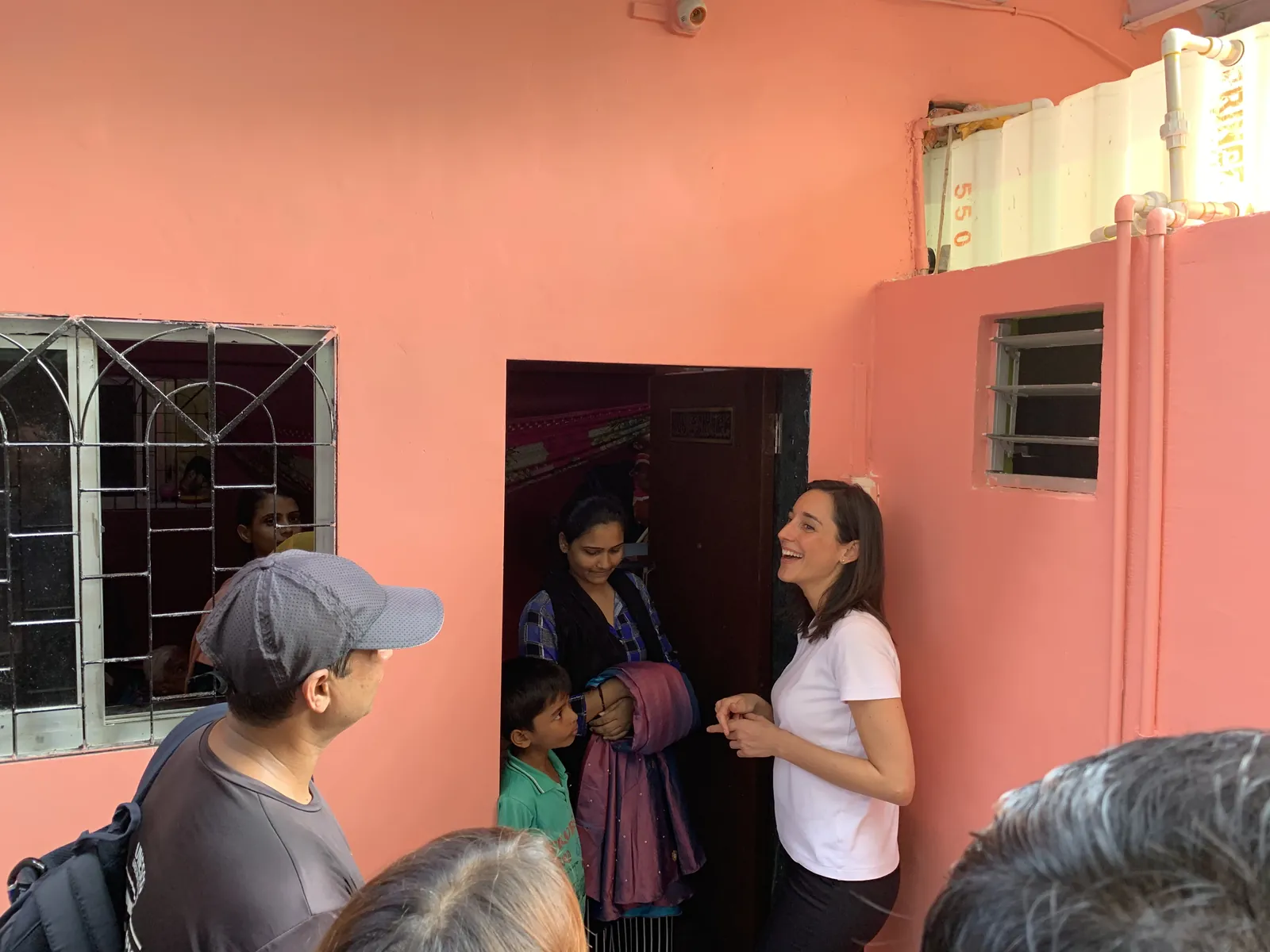 High school social work internship field work. Earth5R volunteers talking to a woman at the doorway of a pink house during a household survey