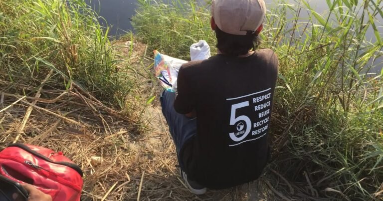 An Earth5R volunteer sits beside a river in Delhi writing field notes