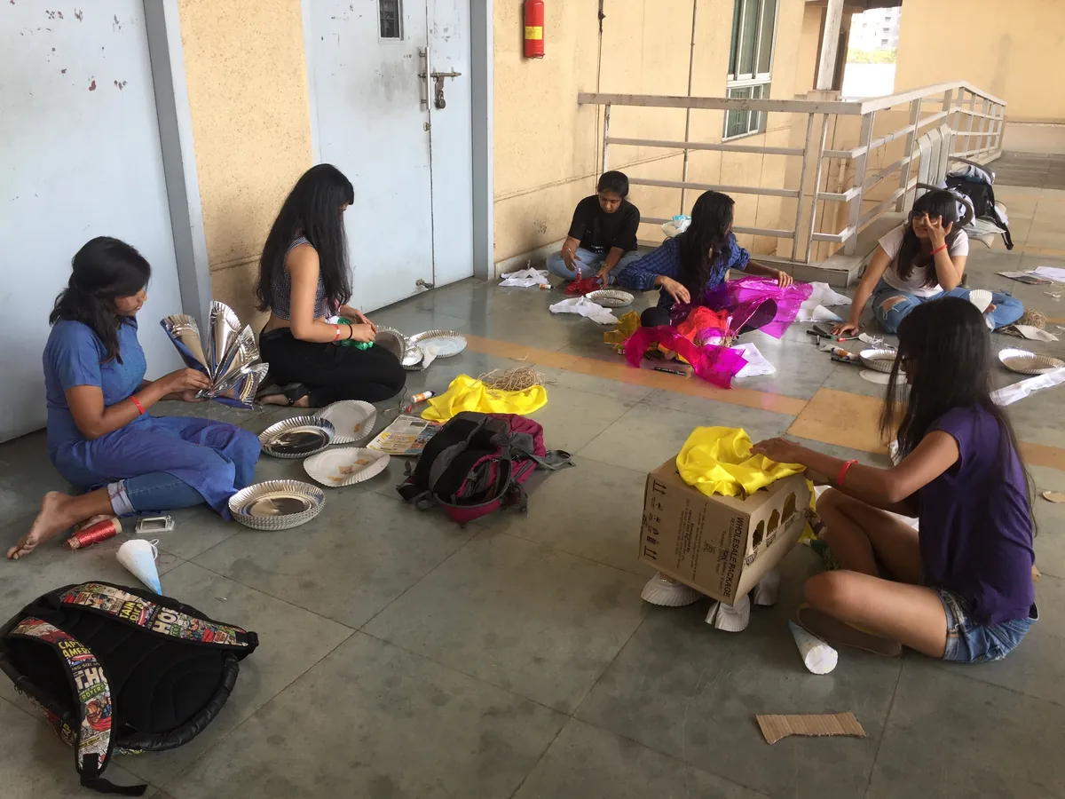Young Earth5R volunteers seated on the open floor of a building sorting coloured fabric pieces into piles and cartons, 2017