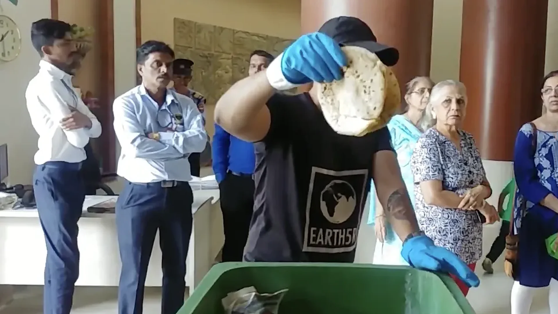 Earth5R founder Saurabh Gupta holds up a whole roti pulled from a housing society garbage bin as residents and building staff in Mumbai look on
