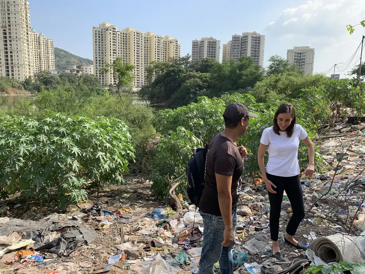 Geography internship field work. Earth5R volunteers on a garbage-strewn vacant plot with high-rise towers behind