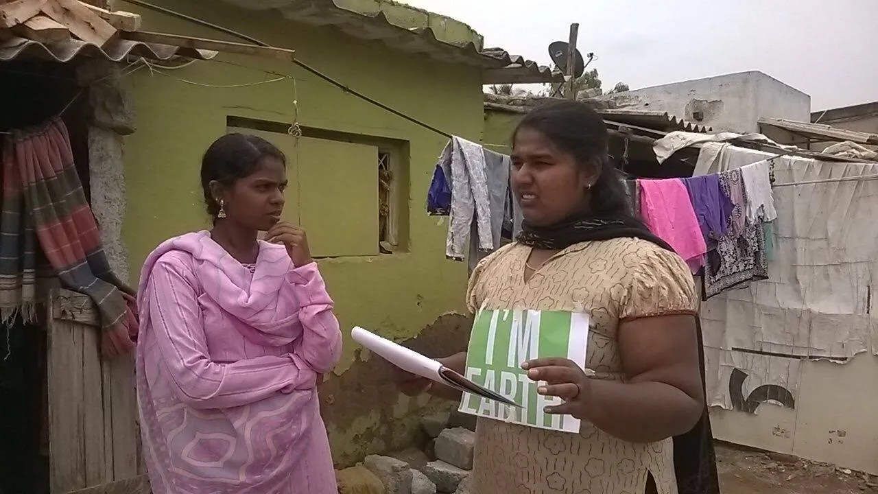 Earth5R volunteer handing an awareness leaflet to a resident outside her home