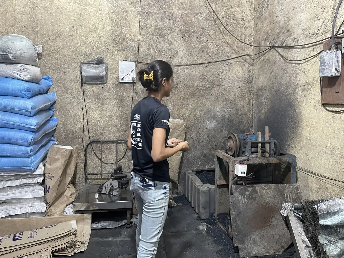 Chemistry internship field work. Woman volunteer in a plastic recycling workshop with a machine and stacked bags