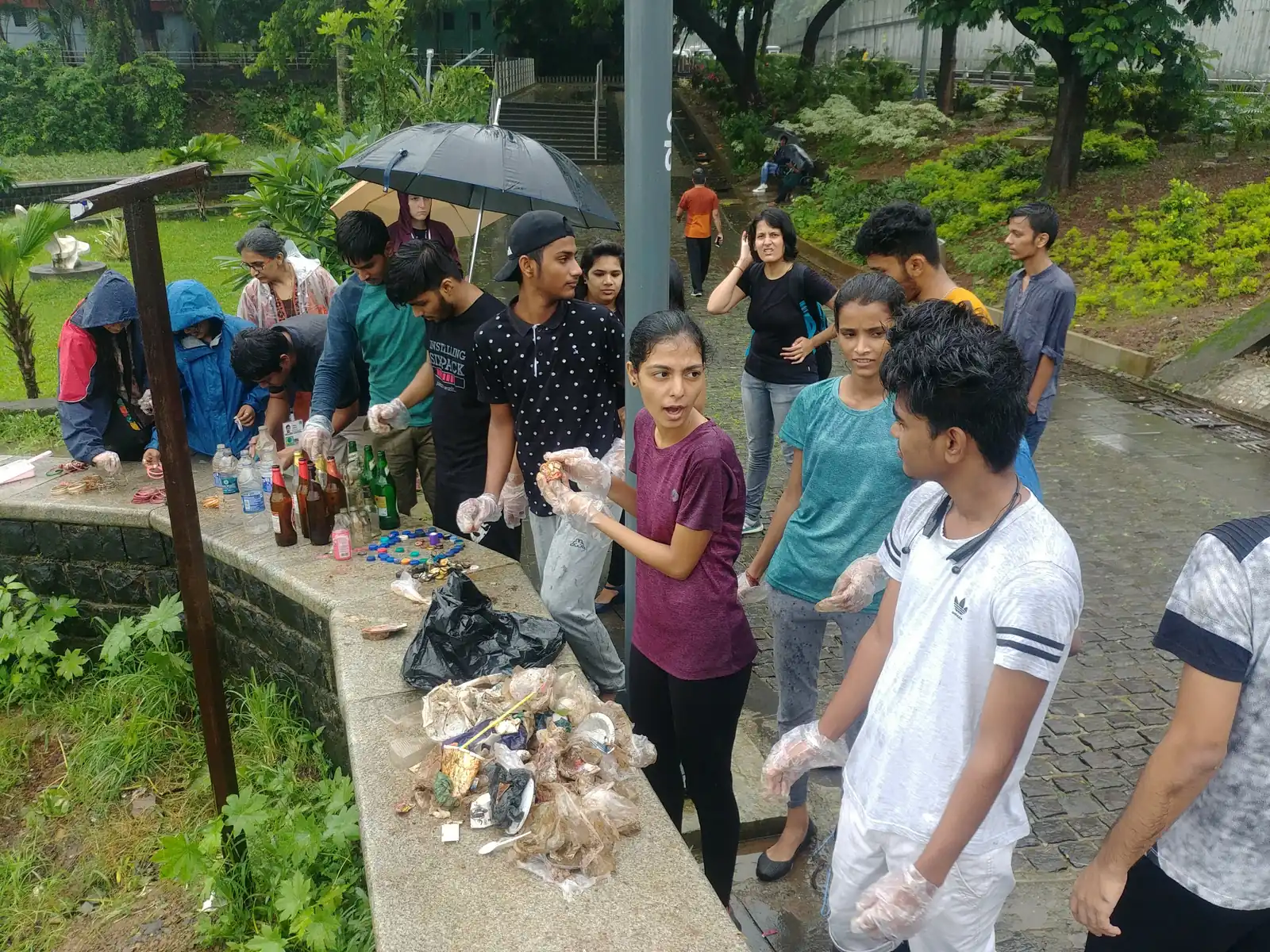 Earth5R volunteers and residents with collected waste on a path in the monsoon rain