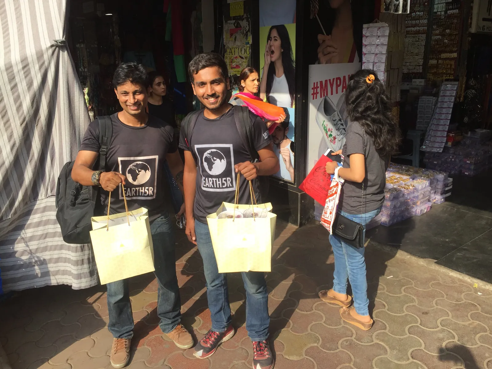 High school law internship field work. Two Earth5R volunteers holding cloth bags in a market lane to promote plastic alternatives in Mumbai