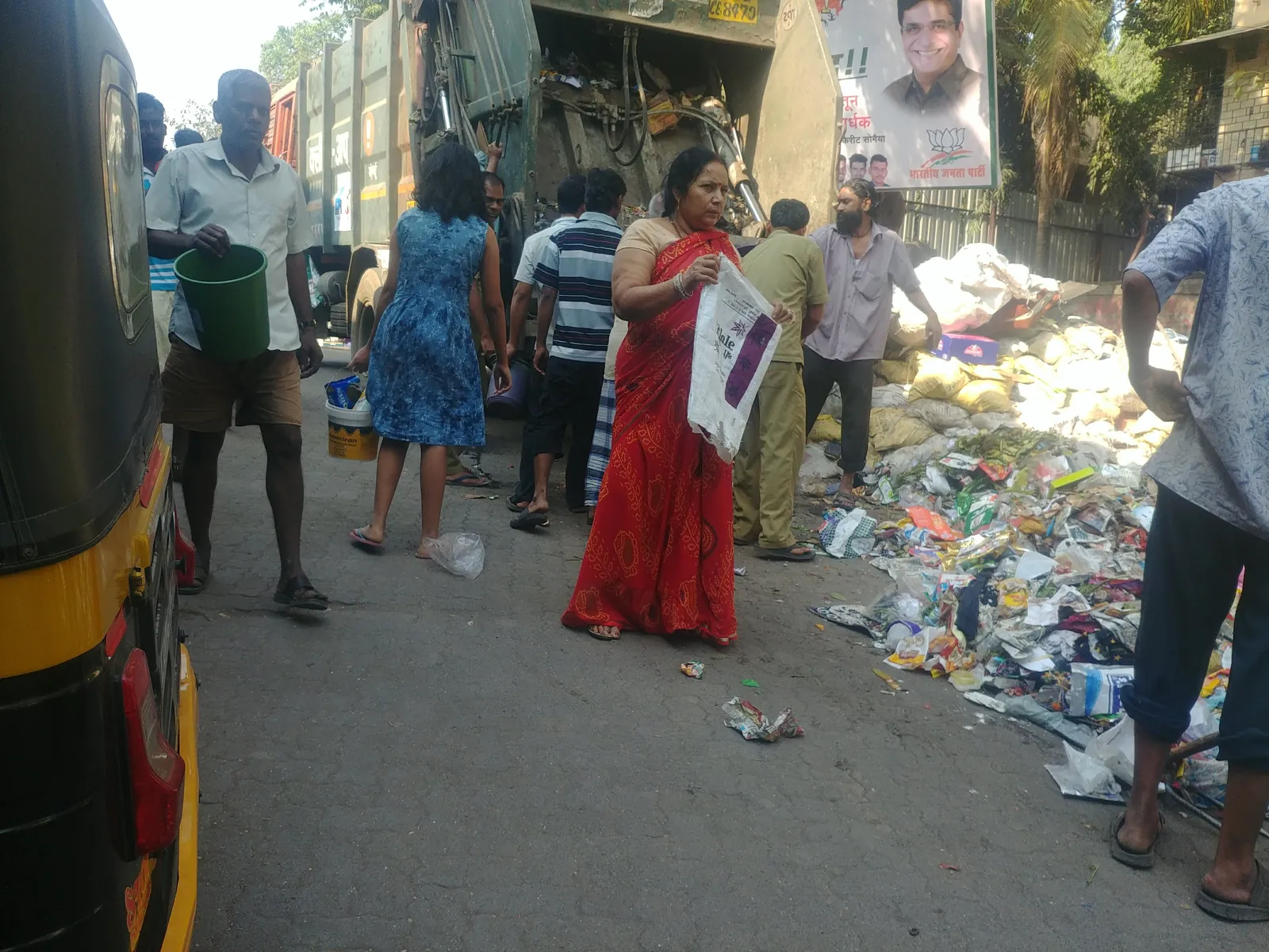 Residents gathered at a large garbage heap on a street to plan its cleanup