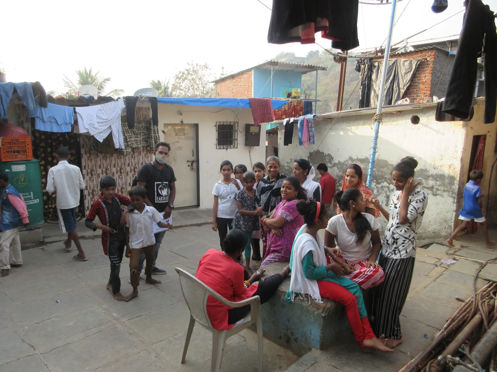 Residents seated and standing in a lane for a community meeting with Earth5R volunteers