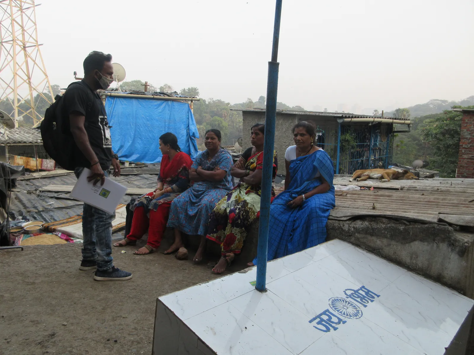 High school architecture internship field work. Residents seated on a rooftop for a community meeting with an Earth5R volunteer