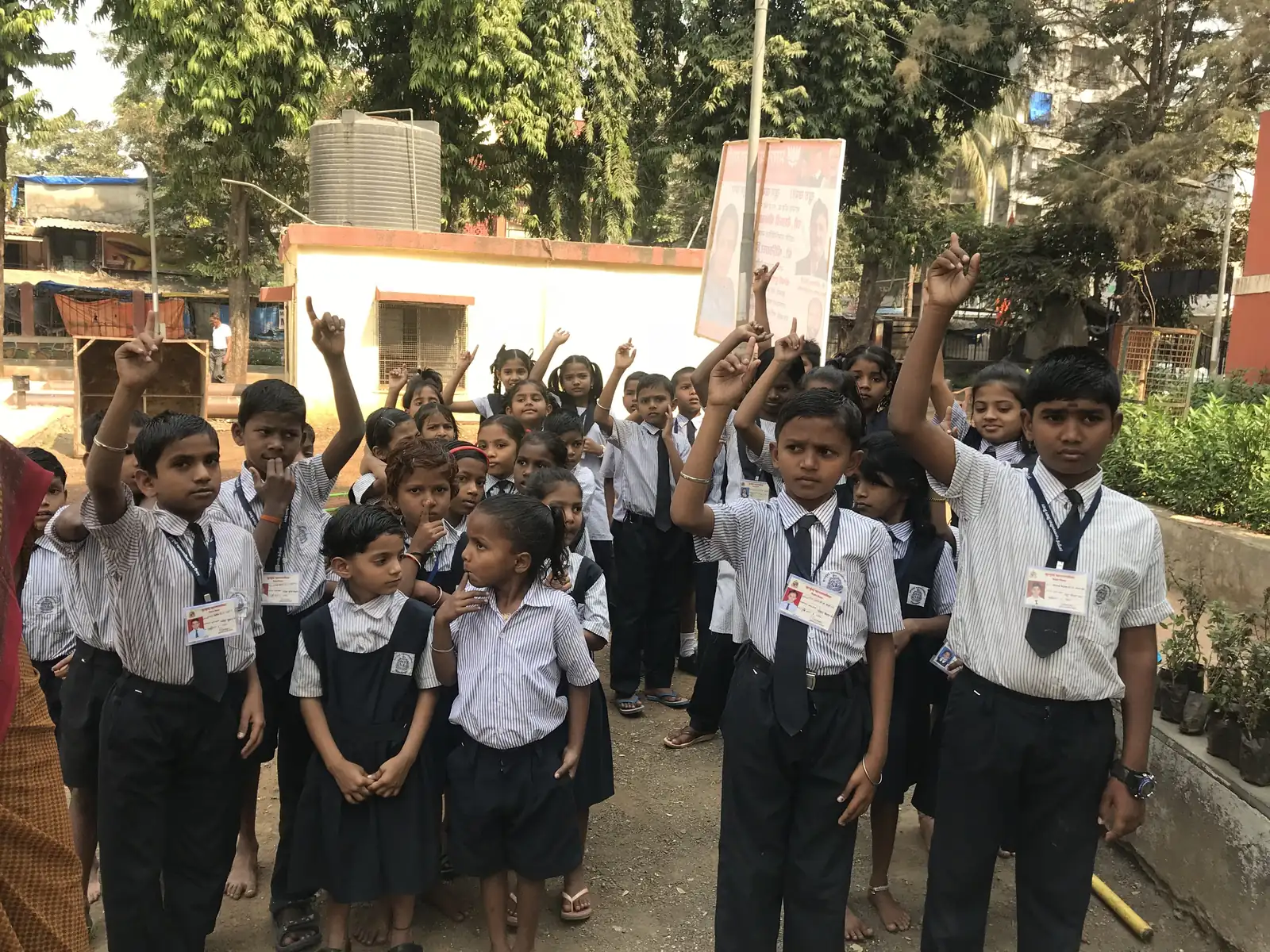 High school teaching internship field work. Schoolchildren raising their hands to answer during a session in the school garden