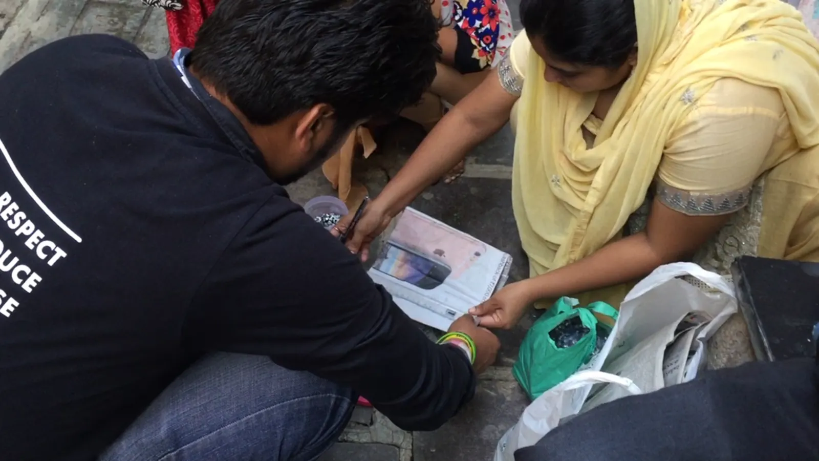 Earth5R volunteers sorting household waste on the floor with a resident to show segregation