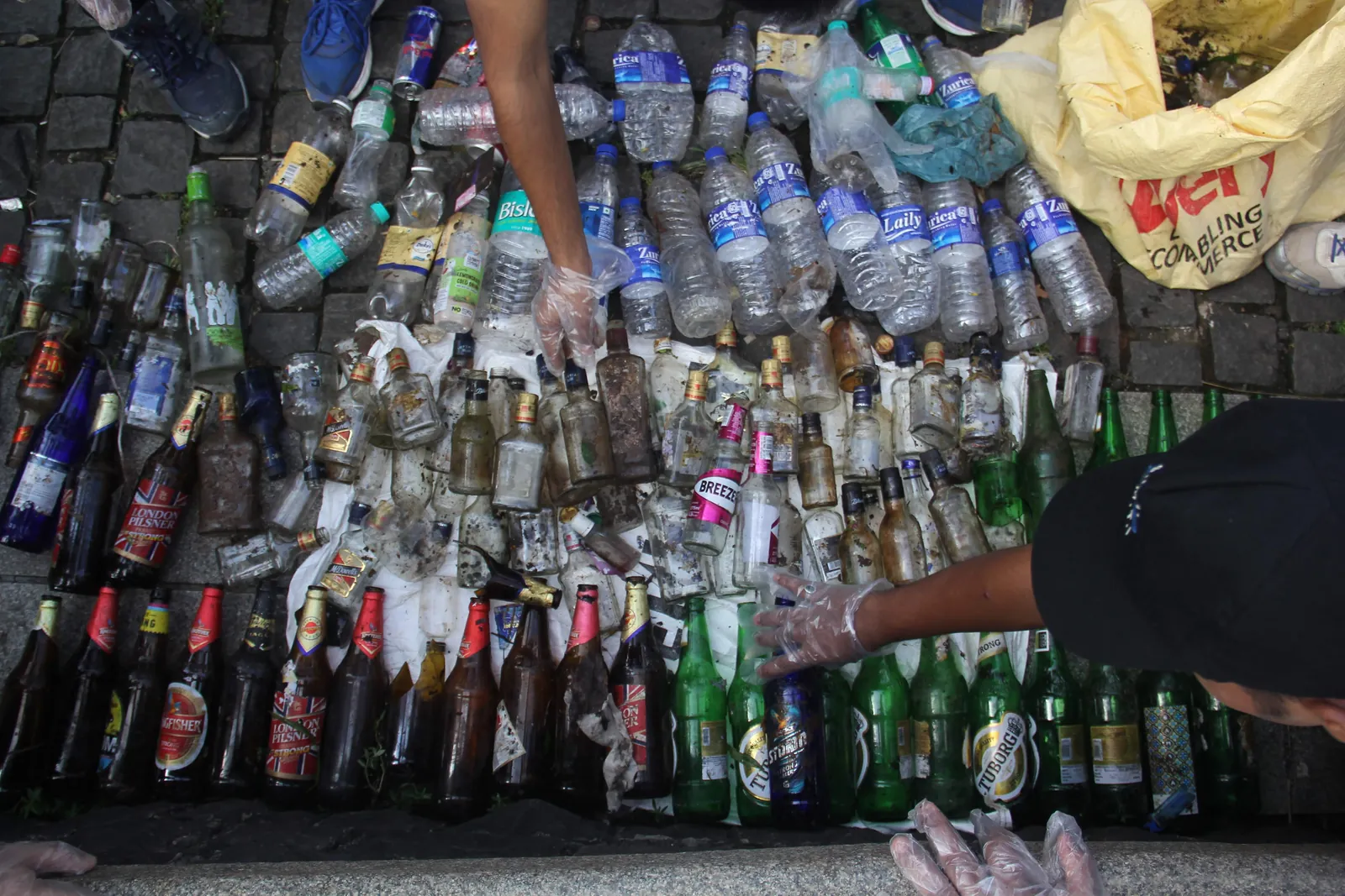 High school computer science internship field work. Hands sorting a pile of plastic and glass bottles for a waste audit