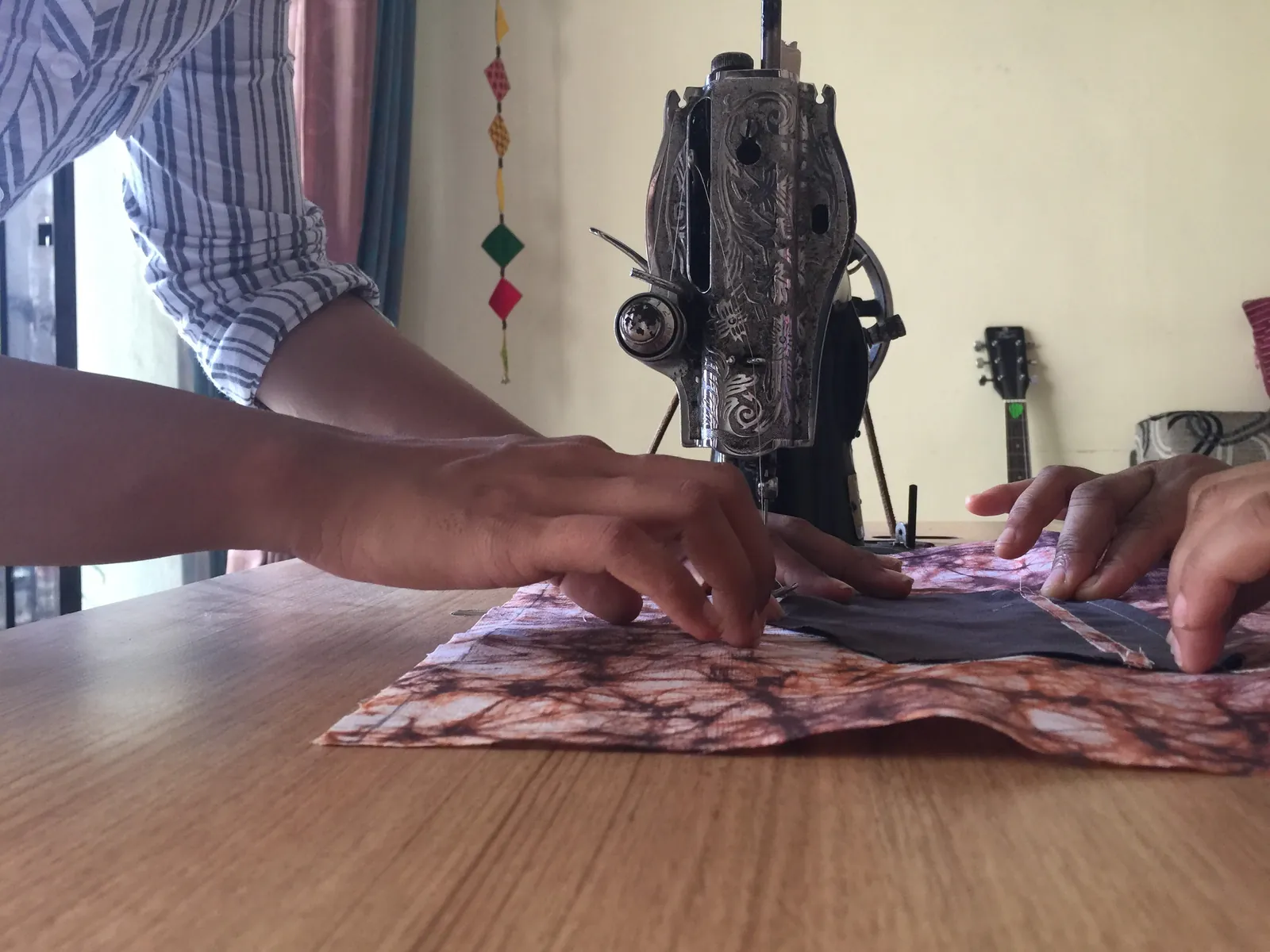 Sustainable fashion internship field work. Hands guiding upcycled cloth through a sewing machine during a skills training session