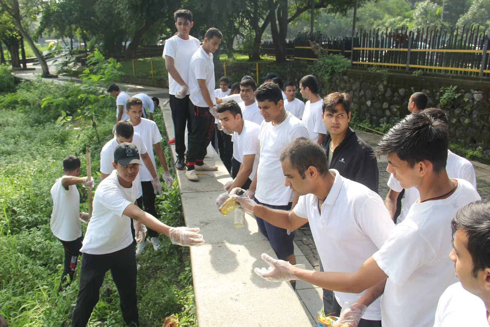 Students in white collecting waste along a park path