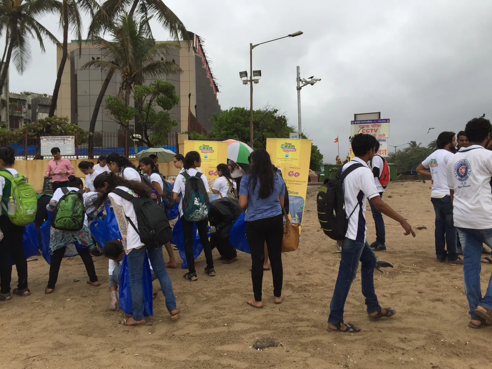 High school photography internship field work. Students with backpacks gathering on the sand for a beach cleanup