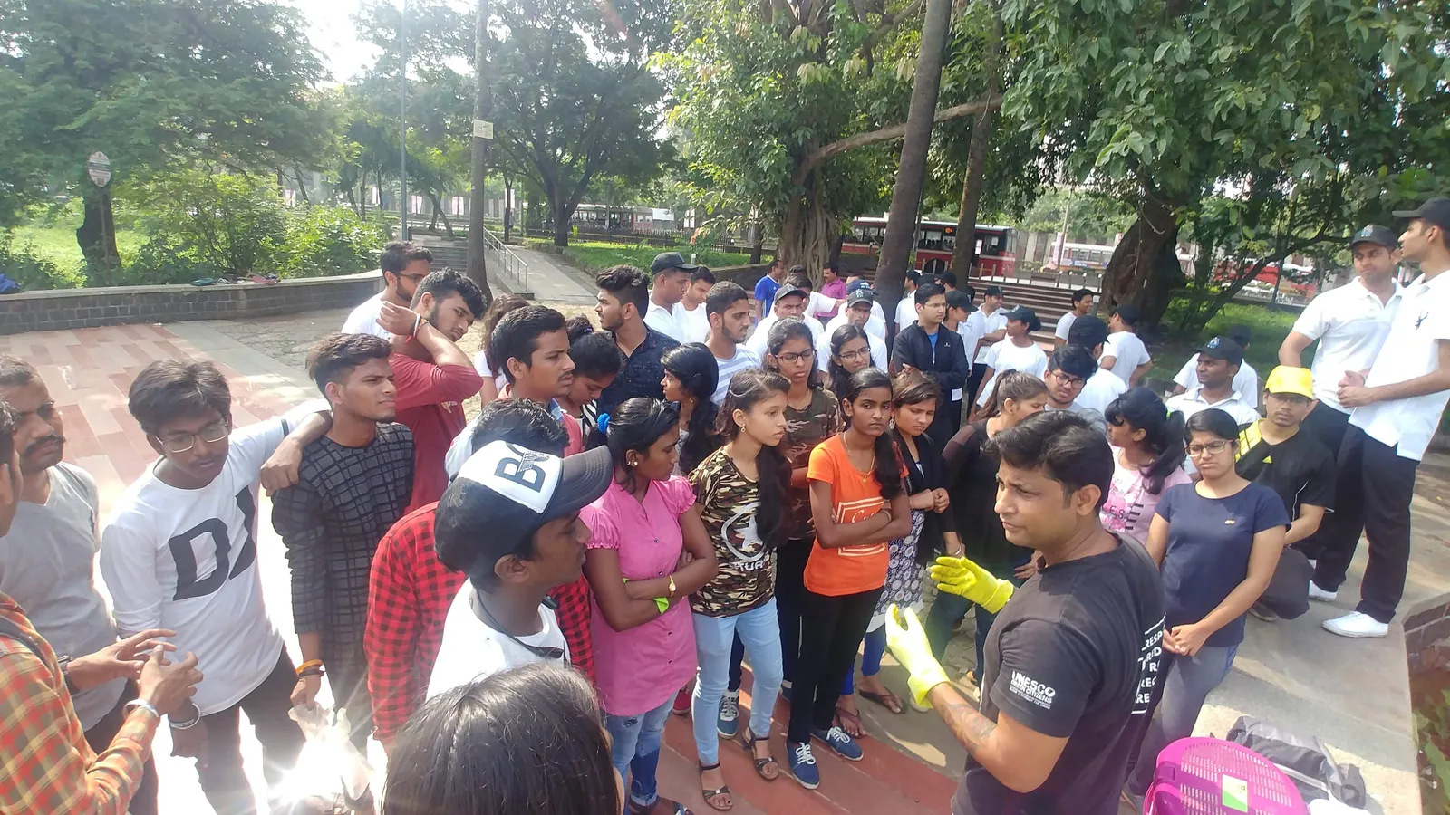 High school geography internship field work. Crowd of students in orange and white vests gathered on a riverside for a cleanup