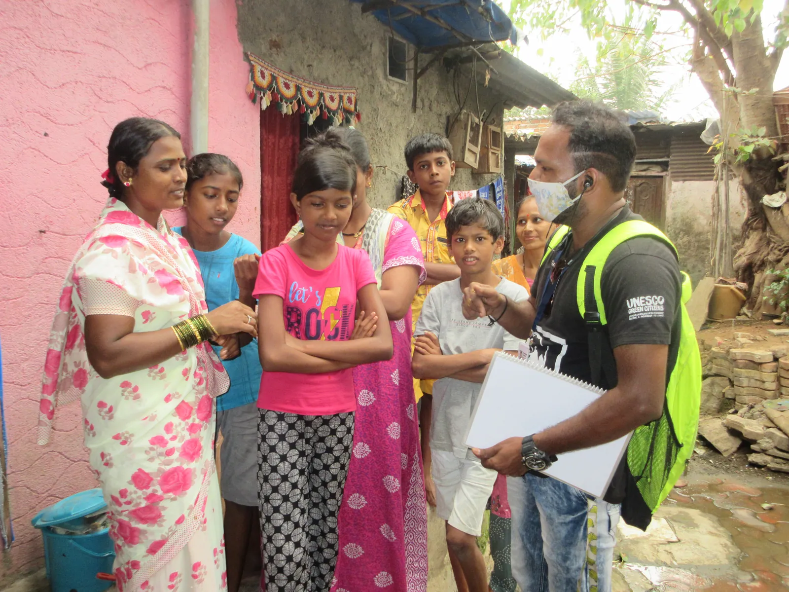 Earth5R volunteer with a clipboard surveying women and children in a lane