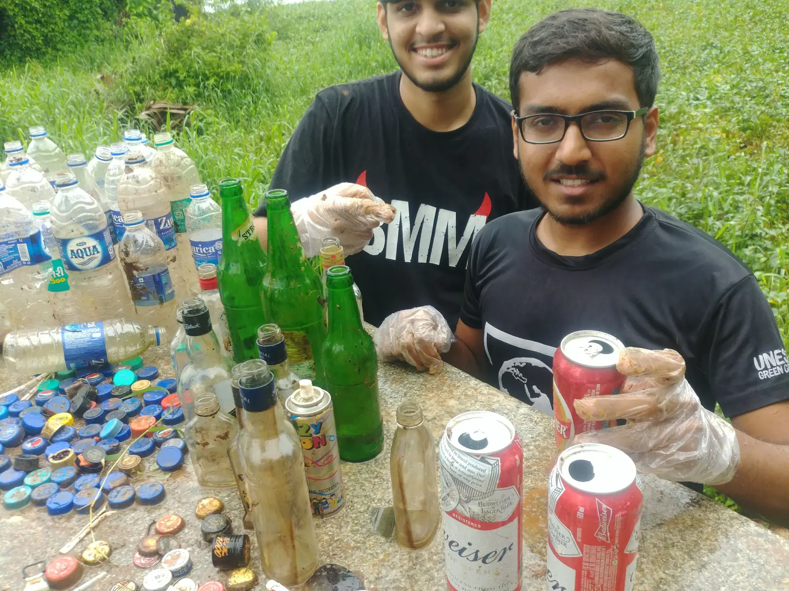 High school finance internship field work. Two Earth5R volunteers holding up glass bottles and cans beside sorted bottle caps and waste