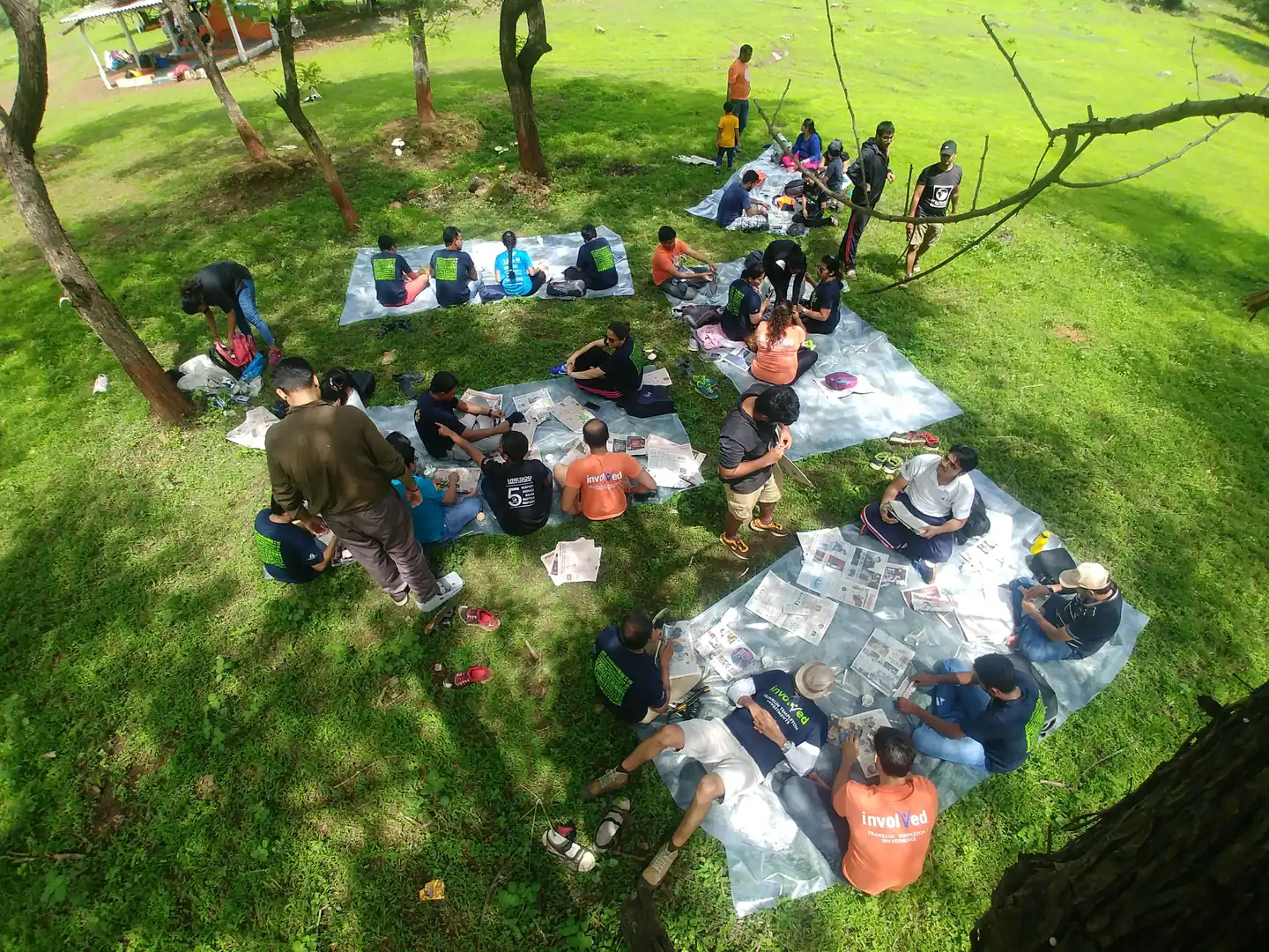 Volunteers seated on tarps on the grass sorting collected waste for a waste audit